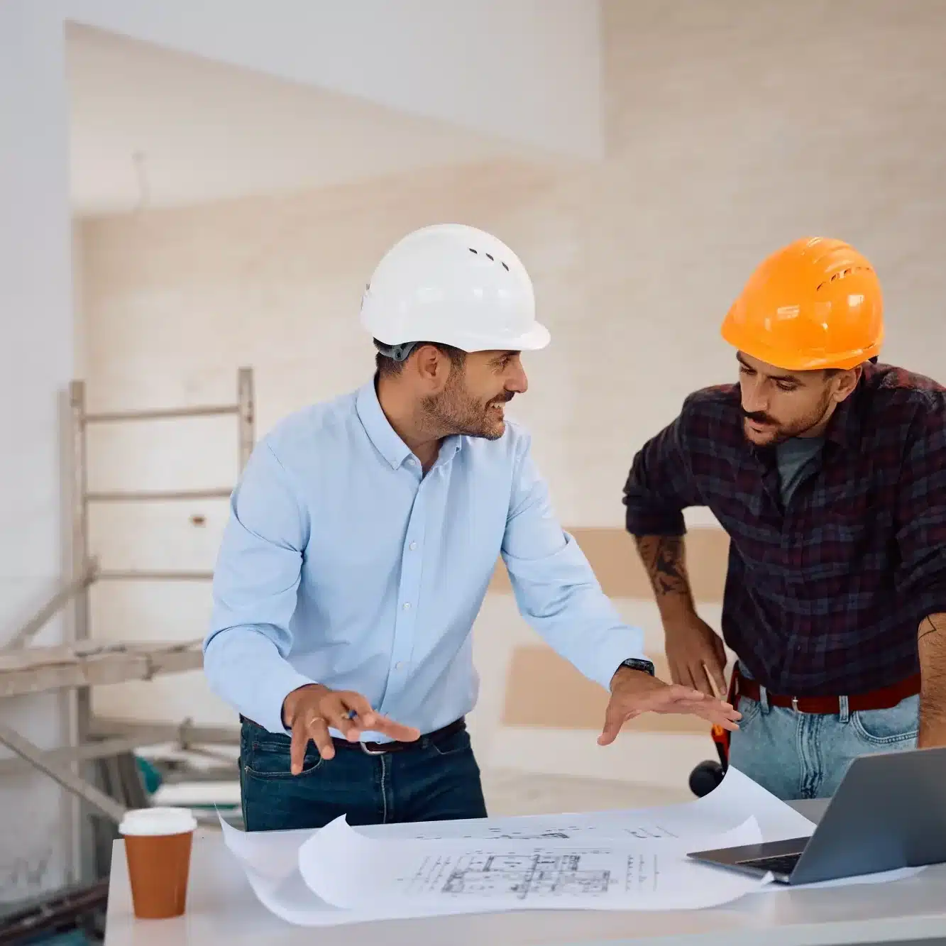 Rénovation façade maison : échafaudage et chantier Chantier de rénovation extérieure d'une maison moderne, échafaudages métalliques devant les façades couleur crème sous un ciel bleu avec nuages.