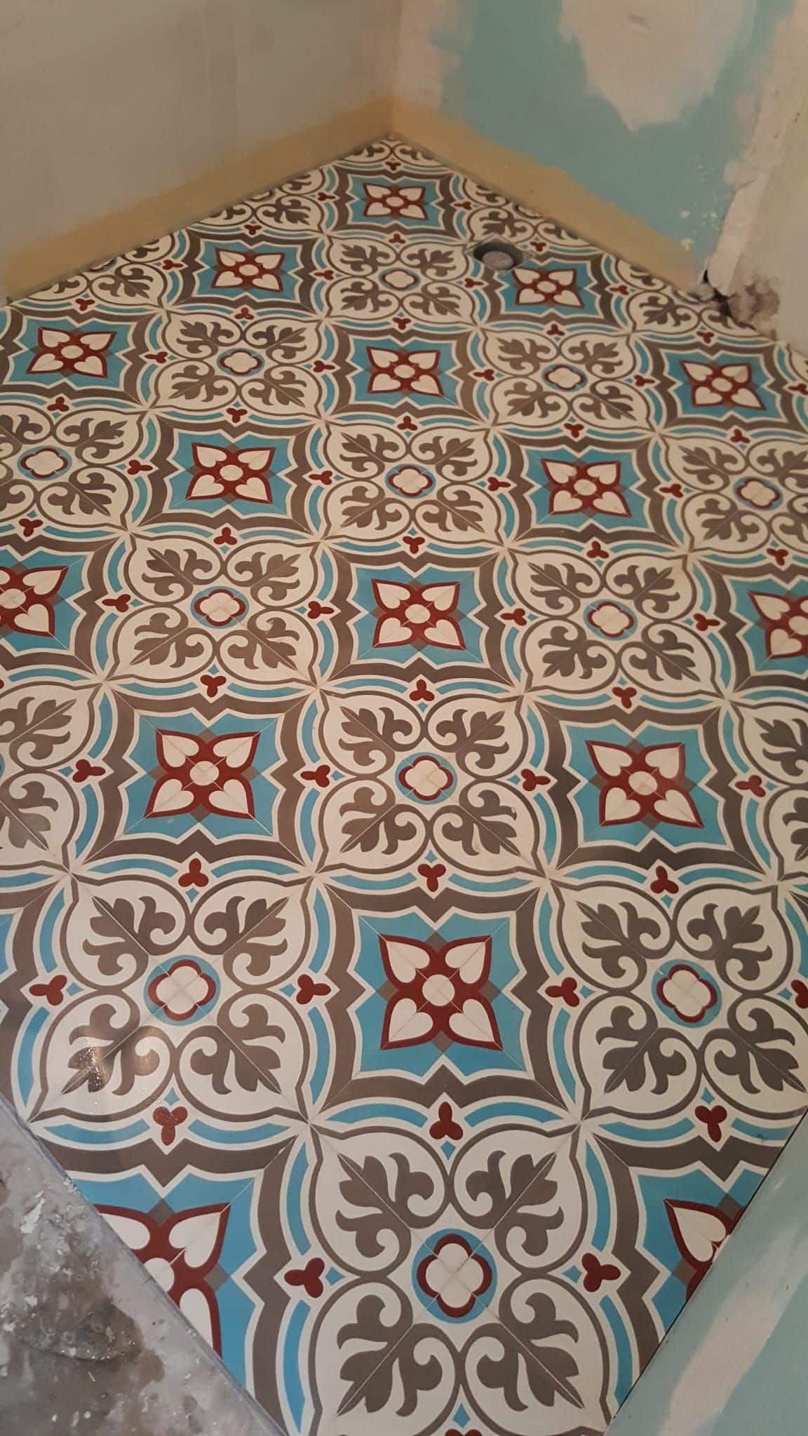 Carrelage de sol à motifs géométriques et floraux bleu, rouge et gris, style ciment pour salle de bain.
